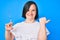 Brunette woman with down syndrome holding syringe pointing thumb up to the side smiling happy with open mouth