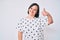 Brunette woman with down syndrome wearing casual clothes smiling happy and positive, thumb up doing excellent and approval sign