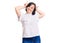 Brunette woman with down syndrome wearing casual white tshirt posing funny and crazy with fingers on head as bunny ears, smiling