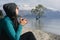 Brunette woman drinking coffee in Wanaka Lake admiring iconic tree on the water. New Zealand, South Island