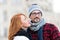 Brunette woman going kissing man. Red hair woman looking to guys face. Portrait of happy couple. Bearded guy in glasses