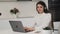 Brunette woman in headset works online on Notebook in kitchen