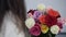 Brunette woman holding bouquet from colorful roses. Woman in white knitted sweater with colorful roses in romantic