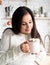 Brunette woman holding a cup of marshmallow cocoa in the kitchen