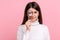 Brunette woman holds magnifying glass, looking at camera with big zoom eye, verifying authenticity.