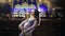 Brunette woman in lilac costume dances belly dance in front of bar.