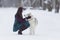 Brunette Woman Looking Eye To Eye with Her Lovely Husky Dog in Winter Forest