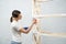 Brunette woman painting wooden rack in empty room.