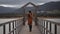 Brunette woman photographer with orange trench coat on a bridge