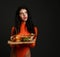 Brunette woman in red bodysuit and jewelry on face holds two home made burgers cheeseburgers looking at upper corner