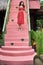 Brunette woman in red dress posing on colorful vintage stair outdoors