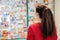 A brunette woman in a red sweater chooses medications at a pharmacy.In the background, the window is blurred. Rear view. The