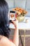 Brunette woman is taking a photo of a cute floral bouquet inside a cabbage-painted pumpkin.