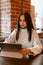 A brunette woman is working on a tablet at a table in a cafe. The theme of freelancing and free work schedule