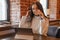 A brunette woman is working on a tablet at a table in a cafe. The theme of freelancing and free work schedule