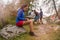 Brunette woman writing personal diary while friends setting hanging tent camping. Group of friends people summer