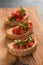 Bruschetta with cherry tomatoes and spinach leaves on olive board