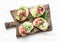 Bruschetta with cream cheese, pear, prosciutto and arugula on wooden chopping board on light background