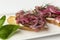 Bruschetta with fish and red onions on a plate. Appetizing appetizer. Close-up