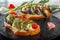 Bruschetta with fried eggplants, fresh tomatoes and cheese on black boards against the background of fresh vegetables.