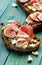 Bruschetta with ham, blue cheese and fresh figs on turquoise table