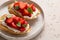 Bruschetta with ricotta, strawberries and basil on light background. Comfort food.