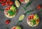 Bruschetta with tomato, avocado, herbs and arugula. Rustic background. Top view