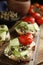 Bruschettas with capers, vegetables and cream cheese served on wooden board, closeup