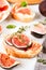 Bruschettas with fig, cream cheese, prosciutto, walnuts and honey on gray concrete table. Healthy quick breakfast recipe