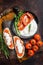 Bruschettas with stracciatella cheese, chopped cherry tomatoes and rosemary. Dark background. Top view