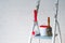 A brush, bucket and textured roller under a brick stand on a metal stepladder near a white wall decorated with bricks.