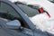 Brush for clearing automobile is on the hood of the car. Snow removing from car after blizzard. Partially cleaned windshield