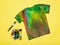 A brush, a large amount of fabric paints and a tie dye T-shirt on a yellow background. Flat lay