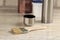 A brush lies next to a plastic paint bucket with a blue lid, a metal can, a thermos with a cup on an old white vintage wooden