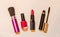 Brush, nail polish, lipstick and mascara on beige background