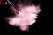 Brush with pink powder explosion on black background.Make-up and beauty concept