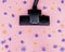 Brush powerful black vacuum cleaner on pink background among flowers. Strength, power, environmental friendliness. Good cleaning,