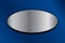 Brushed metal oval plate on blue perforated background