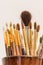 Brushes of the artist in clay pitcher on wooden shelf