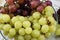 Brushes of fresh grapes of different kinds on a beautiful saucer