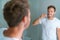 Brushing teeth man looking in mirror of home bathroom using toothbrush in morning routine for clean dental oral care