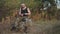 A brutal athlete sharpens shavings with a knife while sitting on a rock