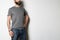 Brutal attractive bearded biker man with tattooed hands poses in gray blank t-shirt from premium thin cotton, on white