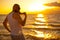 A brutal bald man posing on the beach at sunset parody glamorous chick