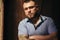 Brutal bearded man with a tattoo on his arm, a portrait of a man in dramatic light against a brown wooden wall, attractive bearded