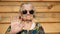 Brutal granny in sunglasses waves by hand at the camera.