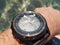 Brutal metal smartwatch on a man`s hand with reflection of solar patches of light on water on sapphire glass. Bathing in