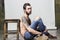 Brutal muscular inked hairy unshaved young man with tattoo on his shoulder and beard