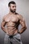 Brutal strong bodybuilder man posing in studio on grey background.