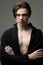 Brutal young man with folded arms wearing black jacket over torso. Portrait of male model with medium length